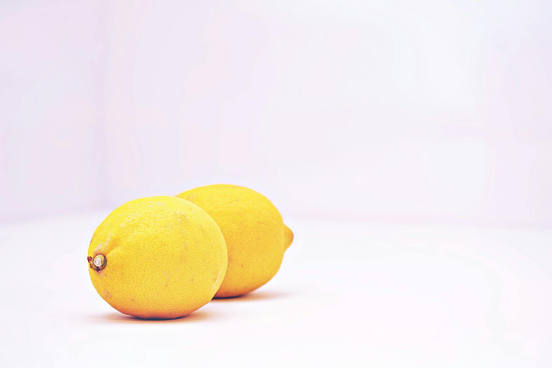 Due limoni vibrant su sfondo bianco minimalista, che rappresentano freschezza e semplicità della riscoperta