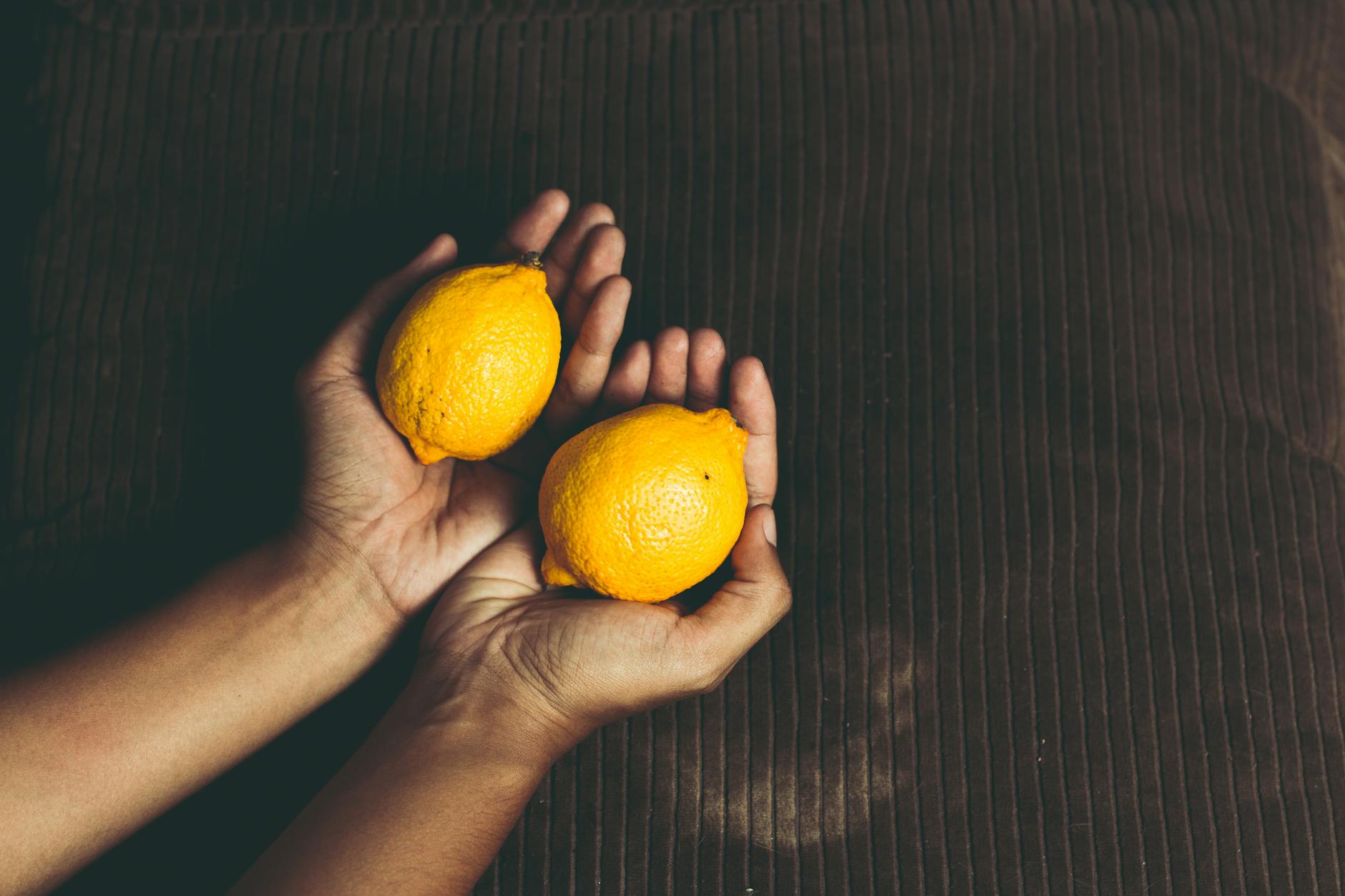 Due limoni freschi in mani aperte su superficie marrone, simbolo di freschezza e rinnovamento