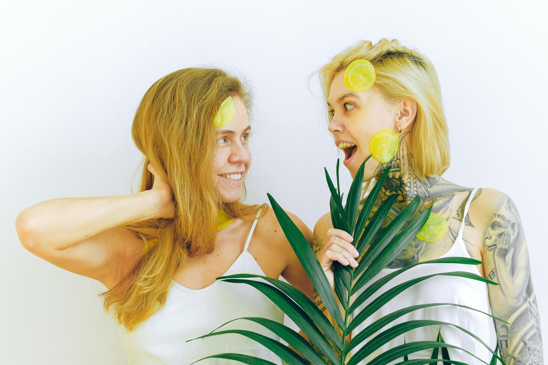 Due donne che sorridono con fette di limone, esprimendo gioia e divertimento in un ambiente interno
