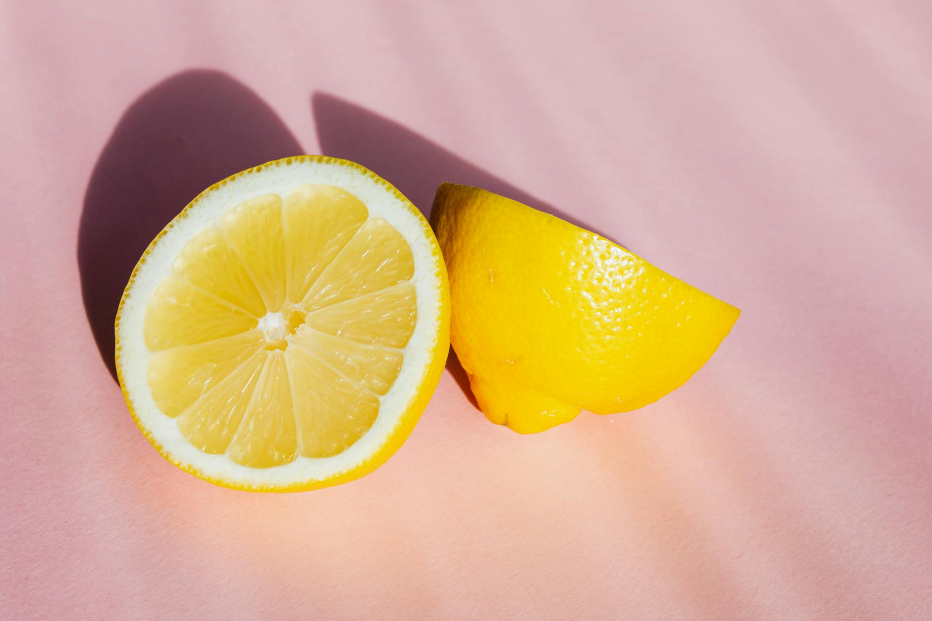 Limoni freschi in controluce su sfondo rosa, simboleggianti freschezza e sensibilità naturale del corpo