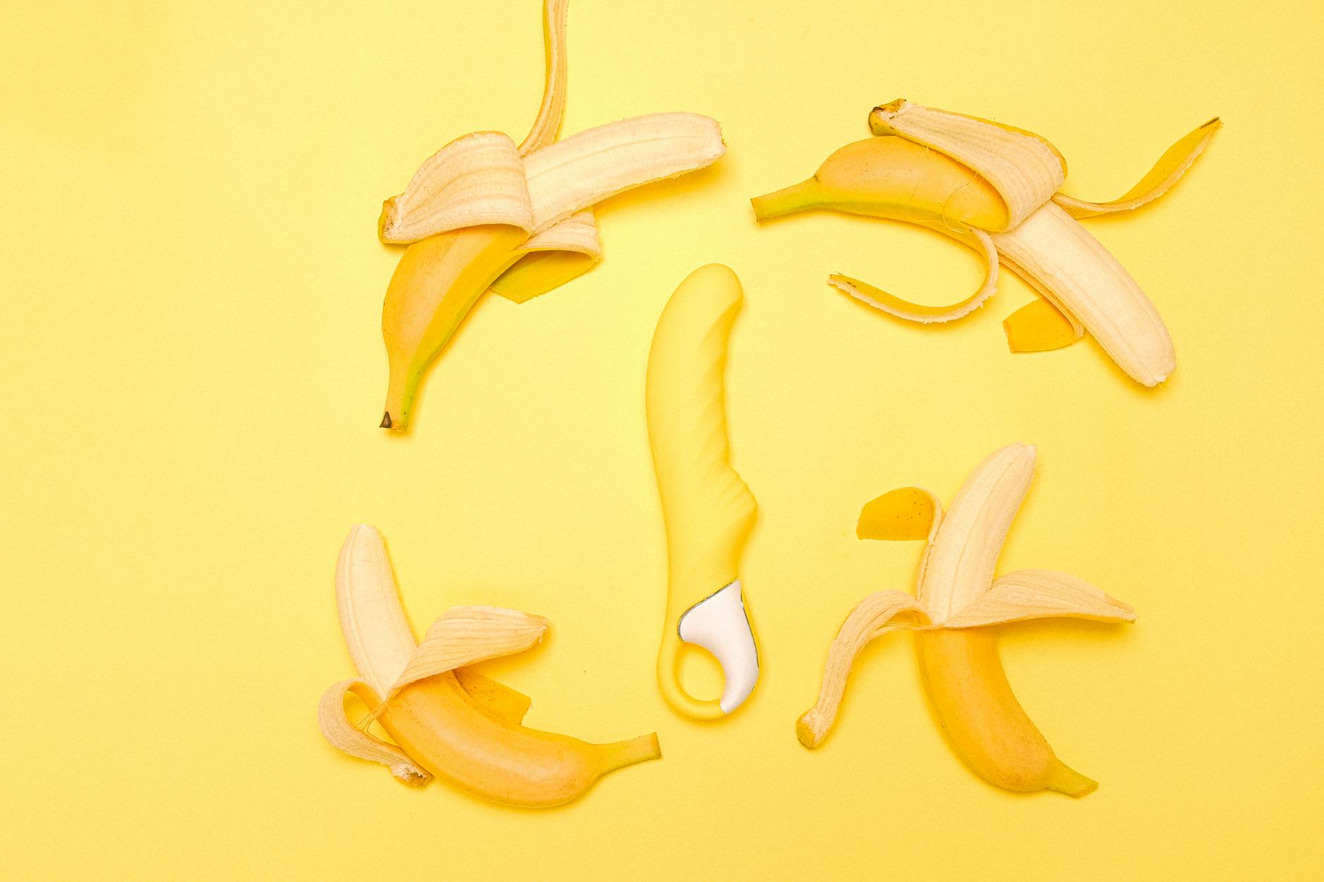 Vibratore clitorideo al limone giallo su sfondo giallo con banane sbucciate