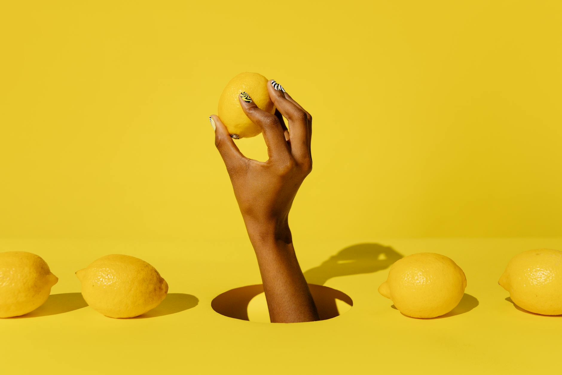 Una mano che tiene un limone fresco su sfondo giallo vivace, simboleggiando la freschezza e la vitalità sensoriale