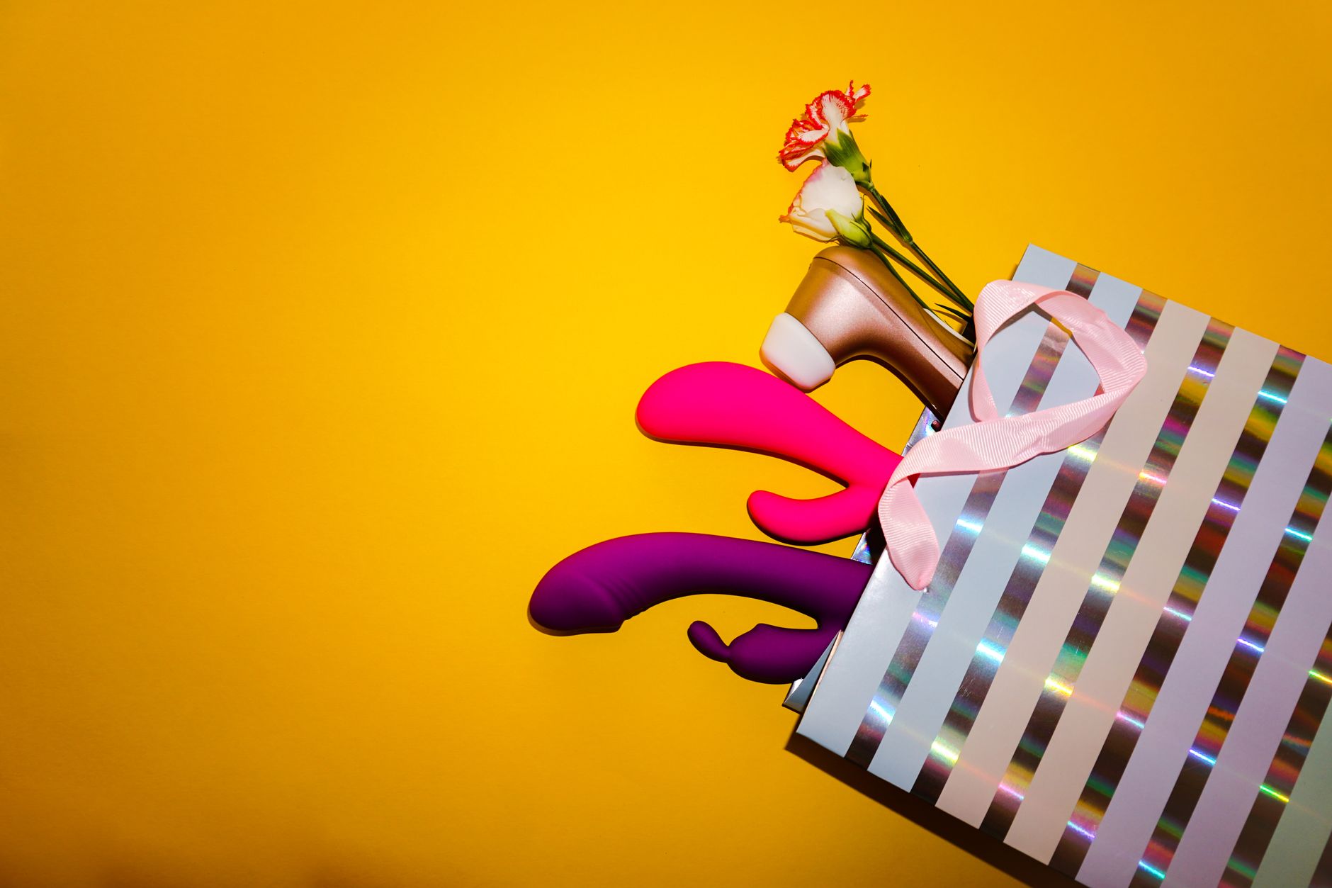 Vibratori colorati al limone in una borsa regalo olografica su sfondo giallo brillante