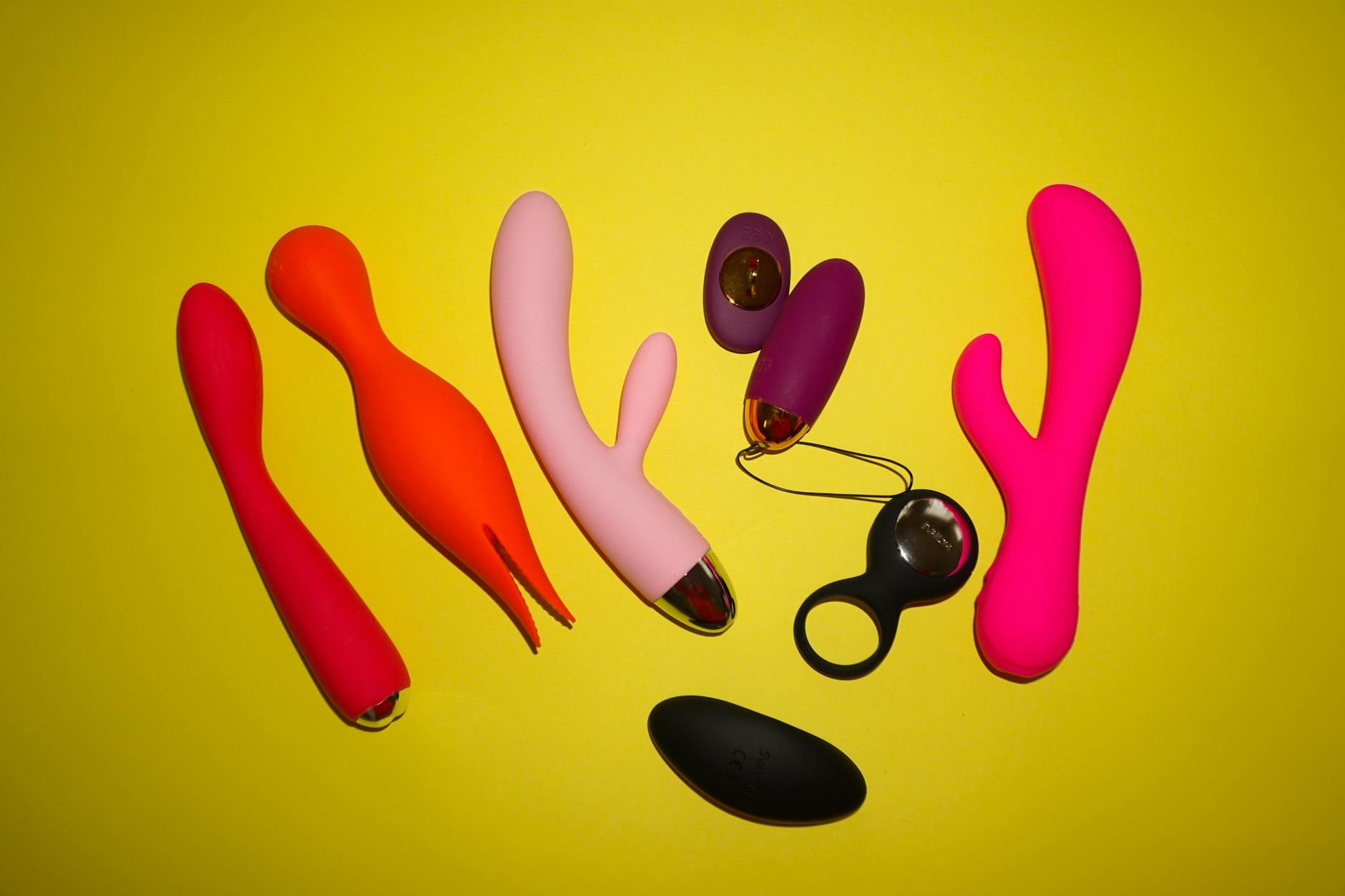 Vibratori colorati disposti su uno sfondo giallo brillante, che mostrano varie forme e design di toy per il piacere