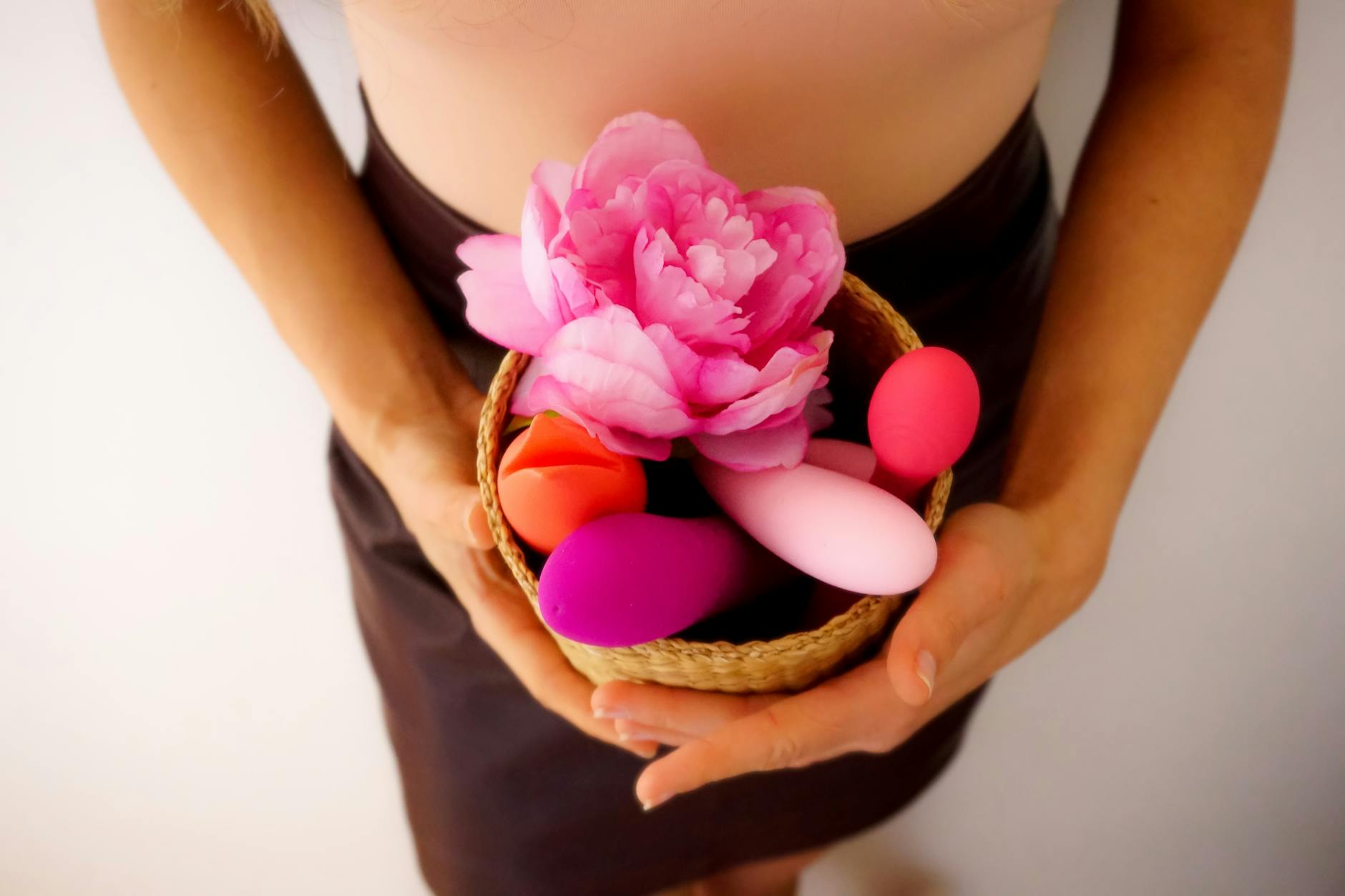 Una donna con gli occhiali che tiene in mano un vibratore clitorideo mentre riflette